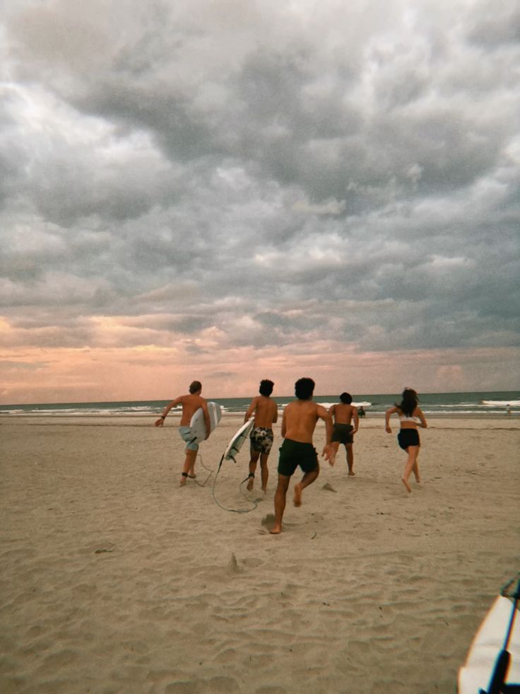 A bunch of friends laughing and racing each other to catch the first wave.